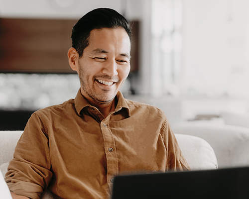 A man looking into his laptop and smiling