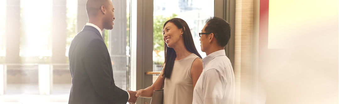 Three people chatting in business attire in an office building
