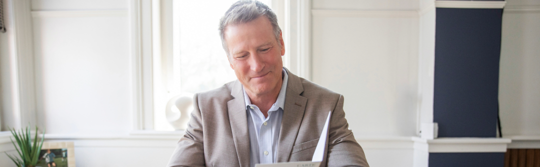 Man in suit smiling at document