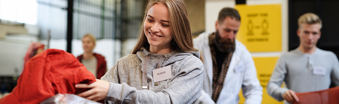 A young woman with a “volunteer” name tag is sorting clothing.