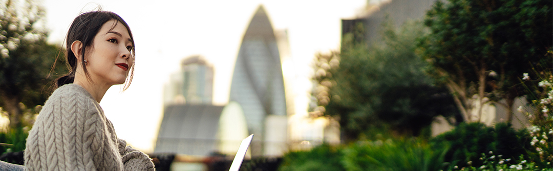 A woman sits outside in an urban park.