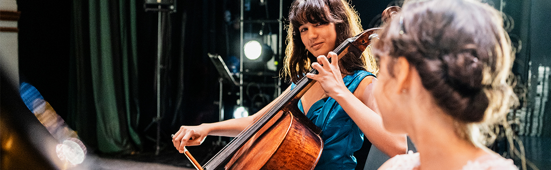 A young woman playing the cello on a stage.