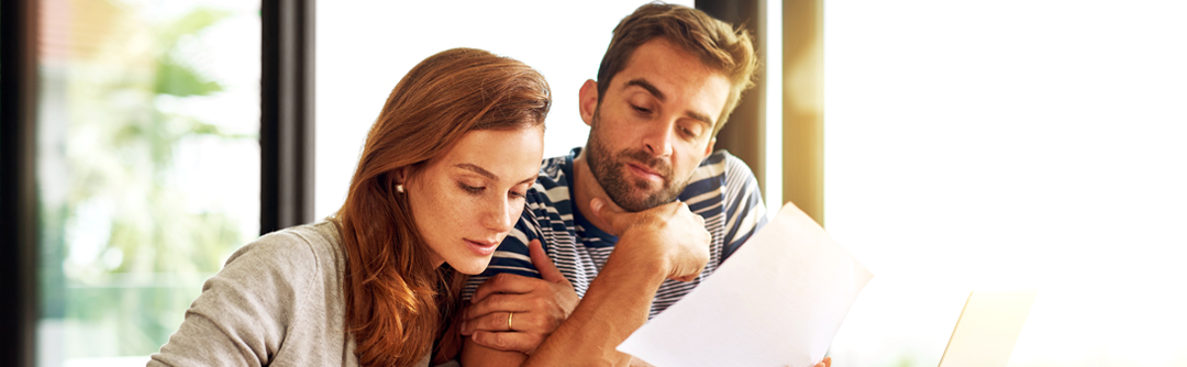 A young woman and young man look at a piece of paper together