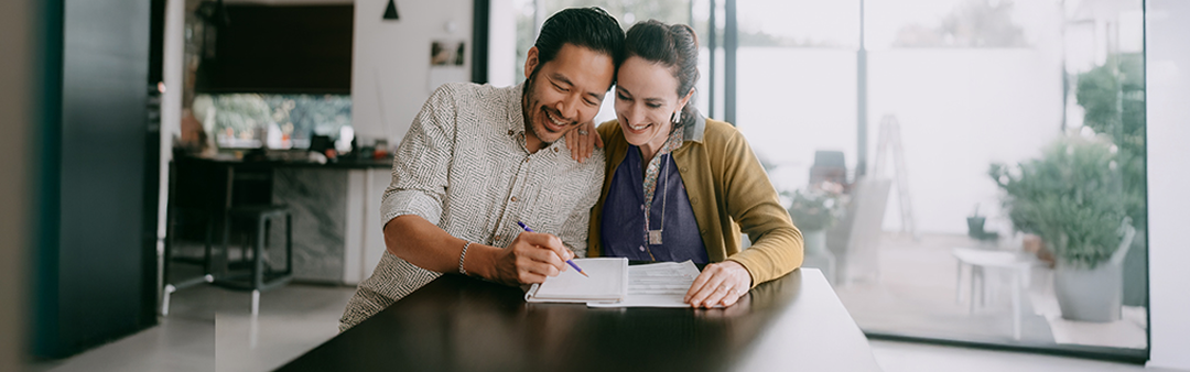 Two people reviewing documents together at a table in a home setting.